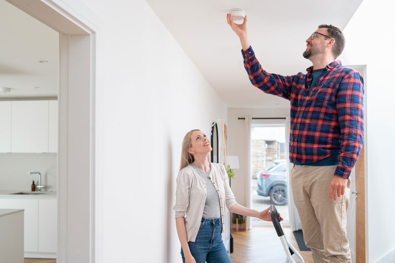 Male-installing-smoke-alarm-WITH-FEMALE-OVERSEEING-web