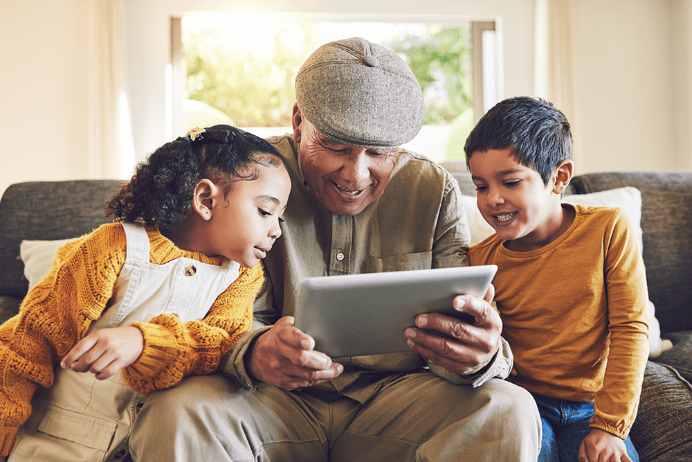 an adult is seen looking at an ipad with two younger children - they look excited and interested