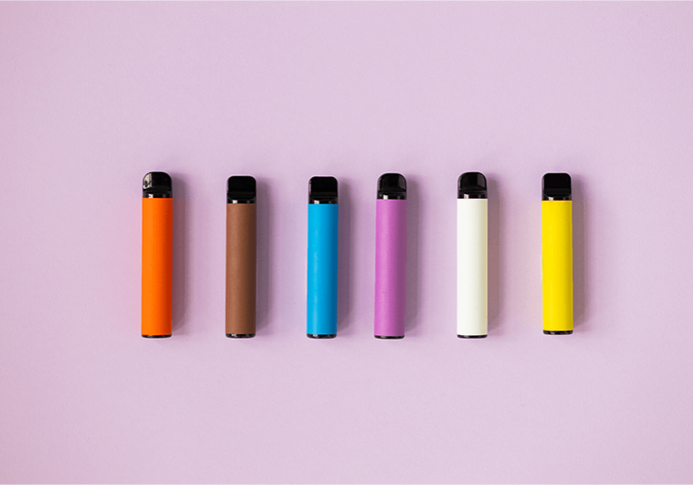 colourful disposable vapes on a lilac background